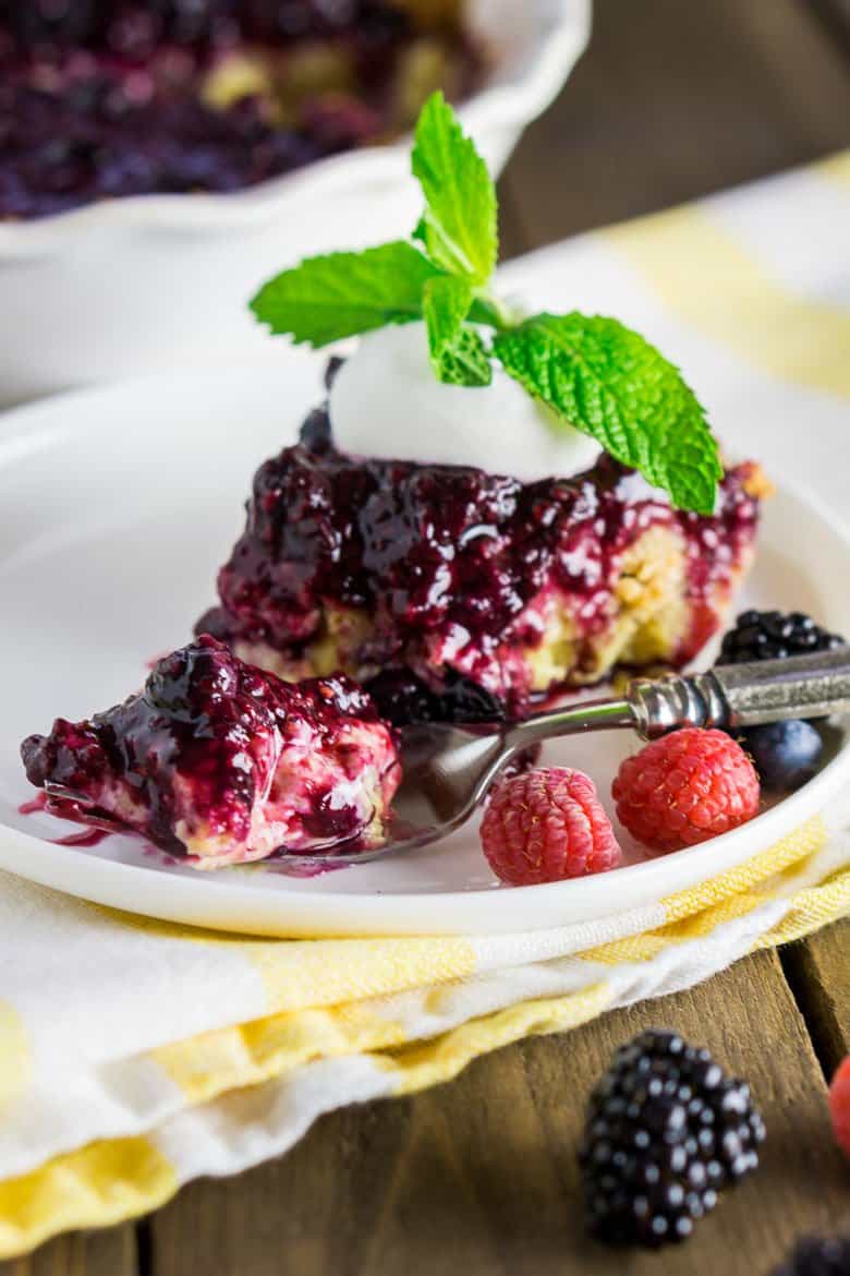 A fork full of the mixed berry-custard pie with the whole pie in the background.