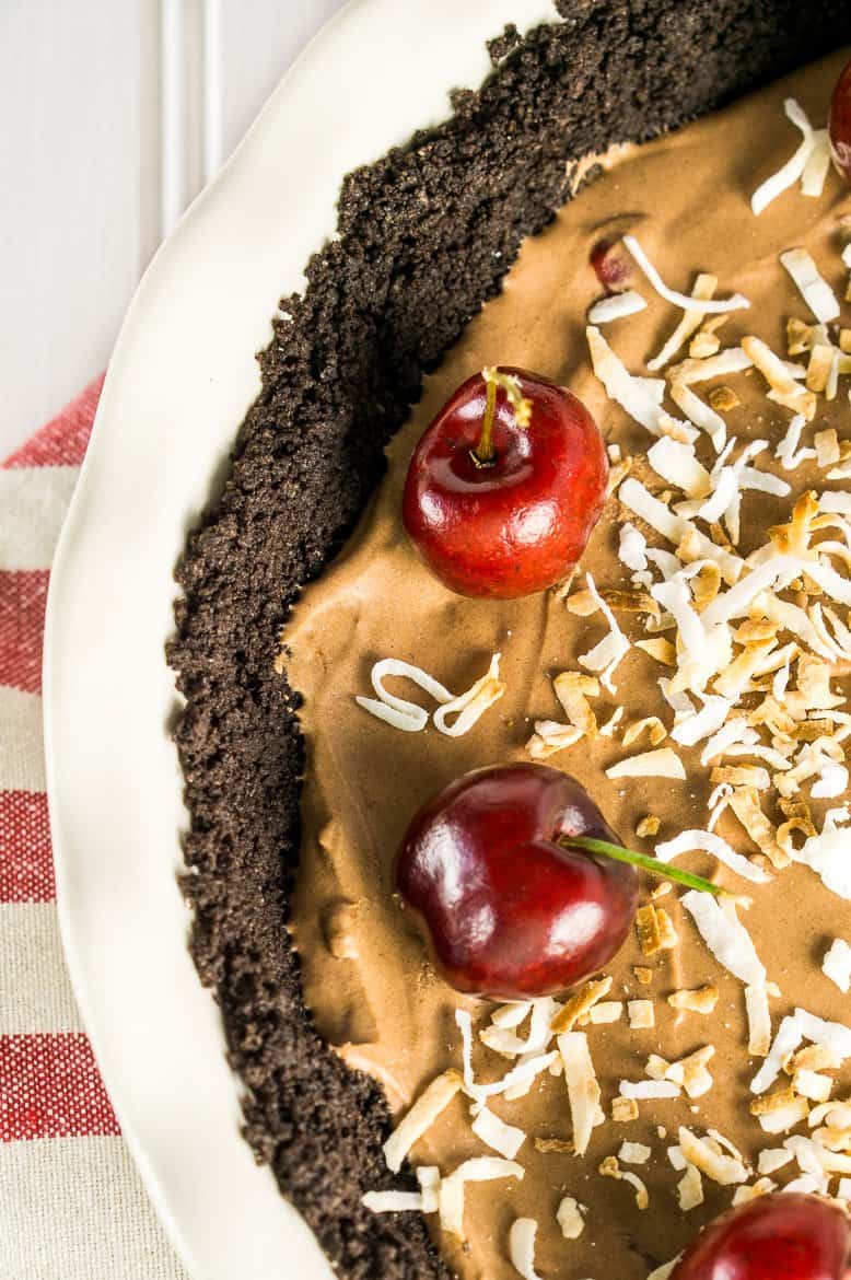 The frozen chocolate cherry mousse pie on a red and white napkin and white board.