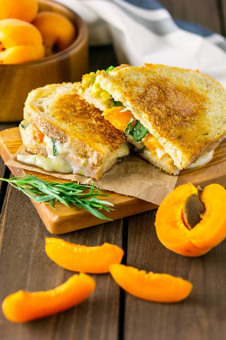 Two halves of Brie grilled cheese with slices of apricots around it.