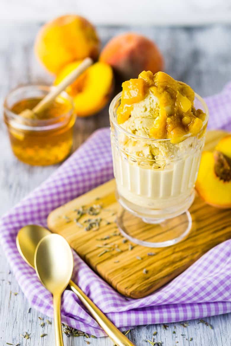 A glass cup with honey lavender ice cream on a wooden board with purple cloth.