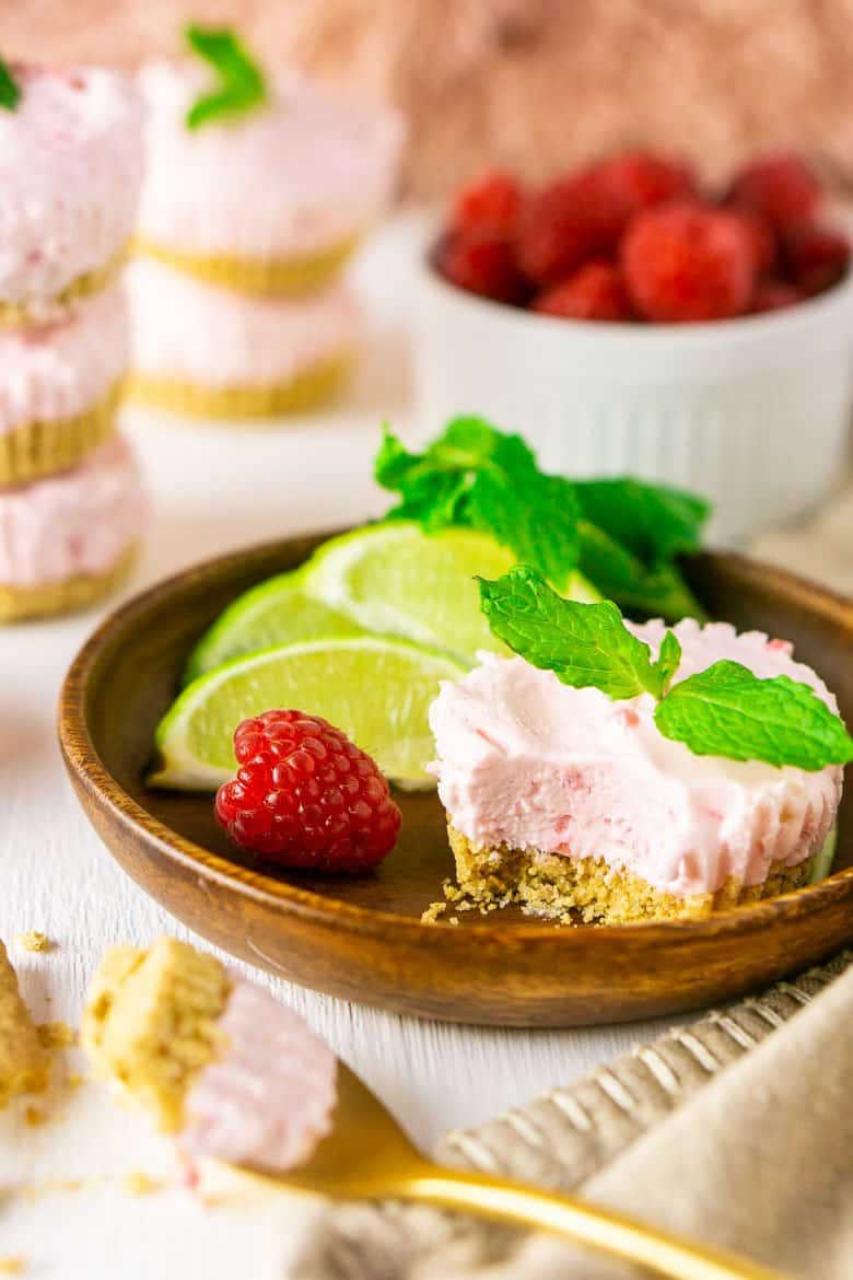 A raspberry mojito no bake mini pie on a wooden plate with a bite taken out it.