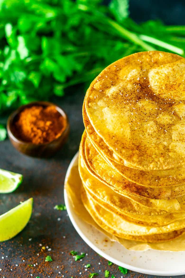 Looking down at tostada shells surrounded by cilantro, chili powder, salt and lime.