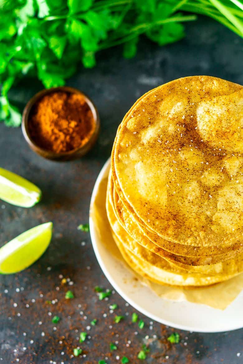 Looking down at tostada shells surrounded by cilantro, chili powder, salt and lime.