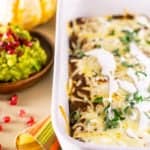 A pan of Thanksgiving enchiladas with pomegranate guacamole and pumpkins as decor
