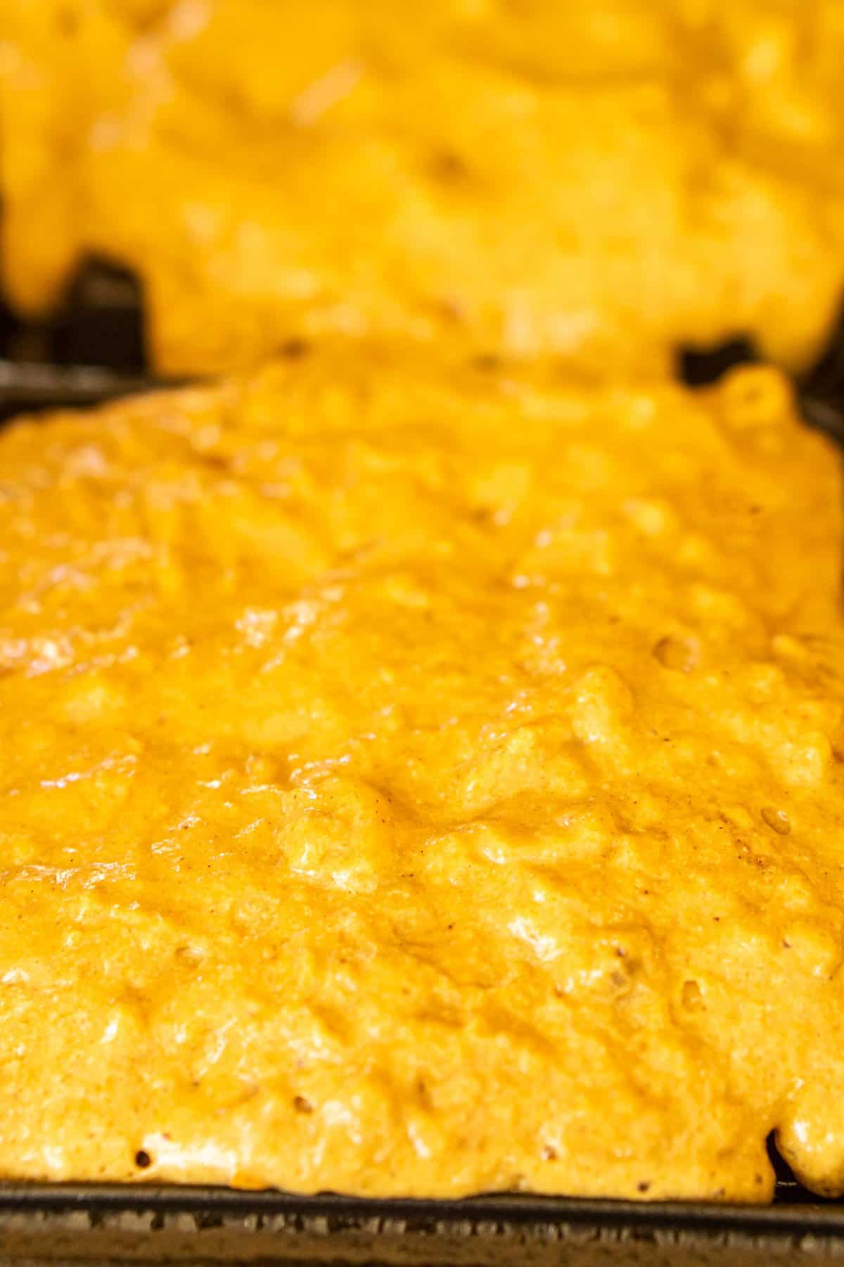 Spreading the batter onto a waffle iron before closing the lid to cook.