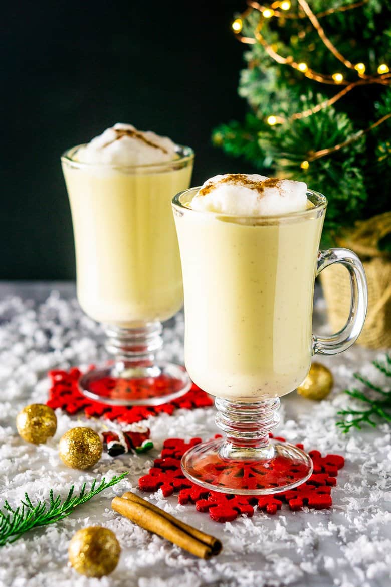Two glasses of maple eggnog with Christmas decor.