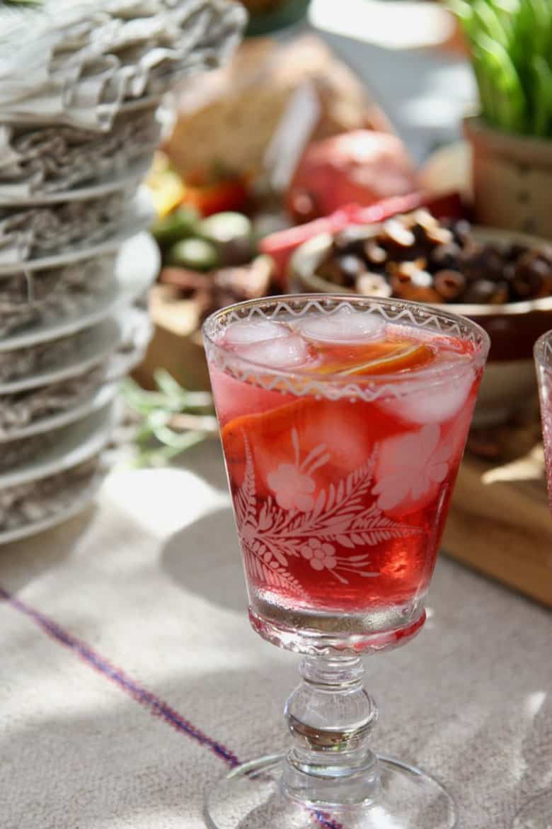 A glass of hibiscus tea cocktail on a wooden table. 
