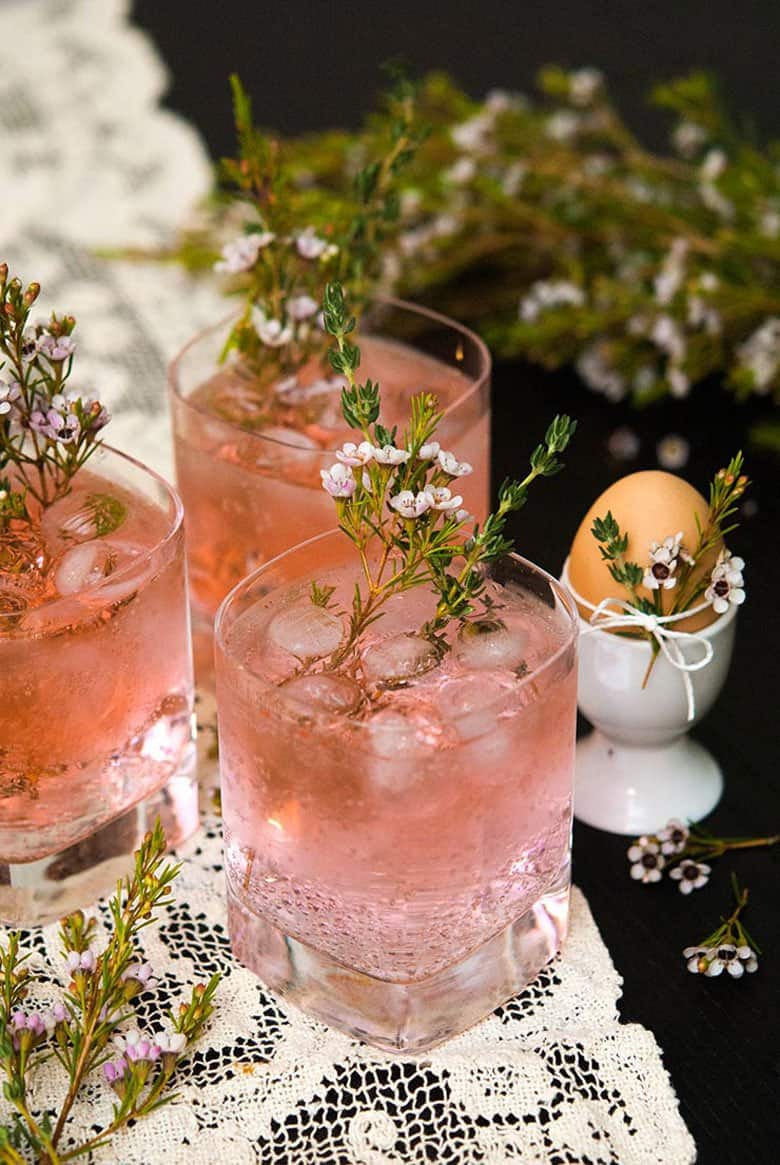 Three pink gin and tonics with a flower garnish.