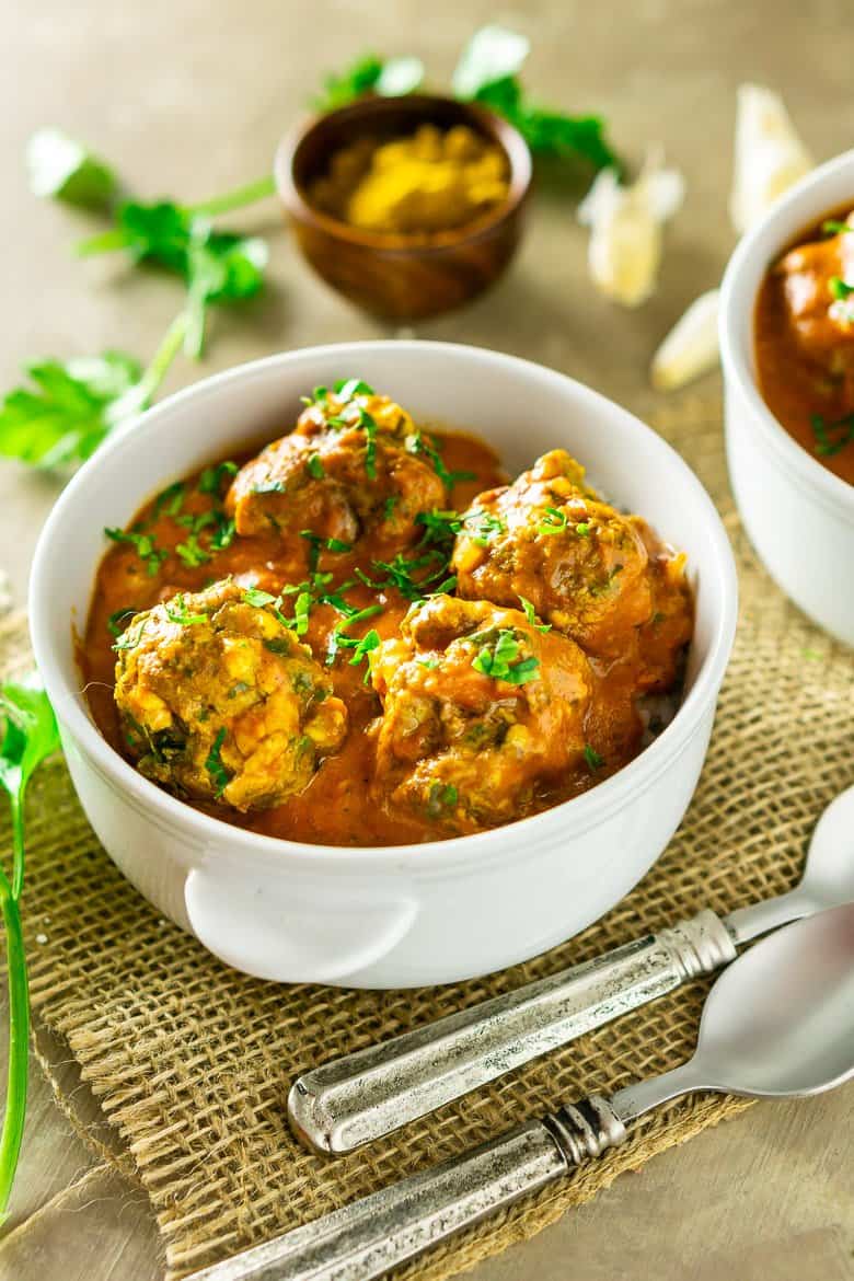 A bowl of curried feta-lamb meatballs with spoons. 