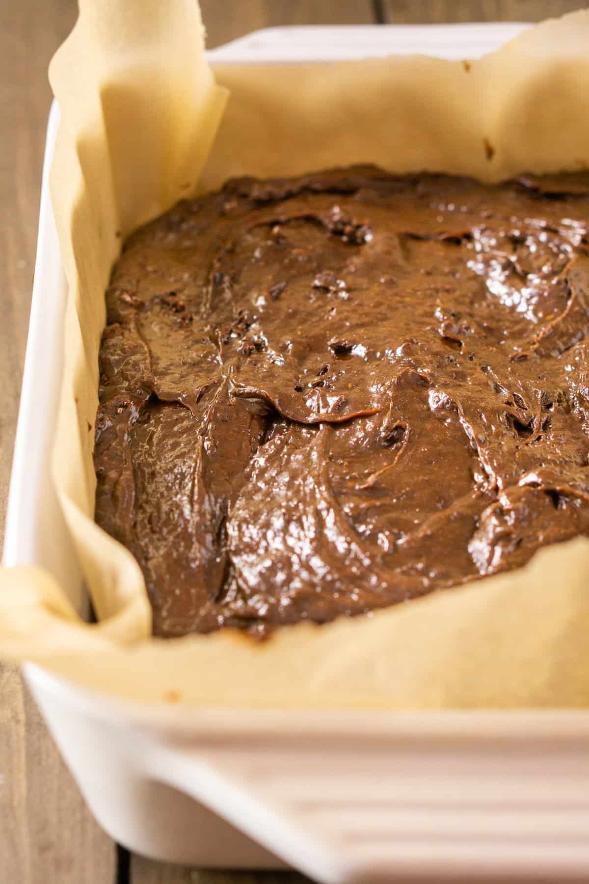 Fudgy stout brownie batter poured into a parchment paper-lined pan.