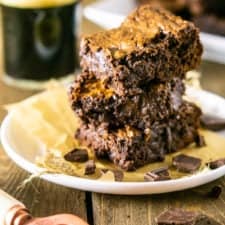 A stack of fudgy stout brownies on a white plate with parchment paper.