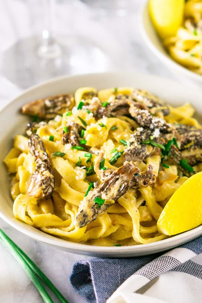 A bowl of morel mushroom pasta with a blue and white napkin.