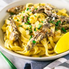 A bowl of morel mushroom pasta with a blue and white napkin.