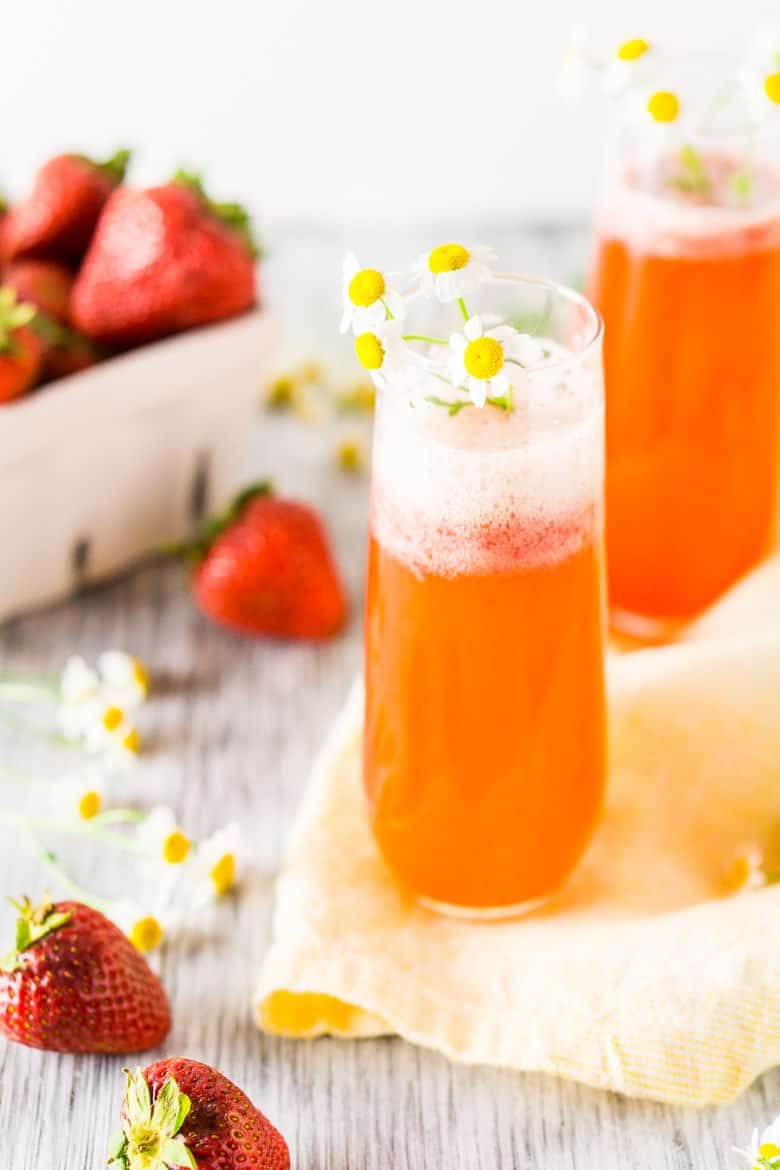 Two roasted strawberry Aperol spritzes with a basket of fresh strawberries.