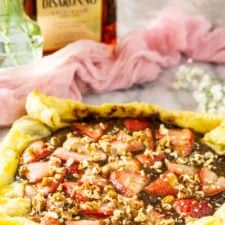 The amaretto strawberry Nutella puff pastry tart with flowers and a bottle of amaretto.