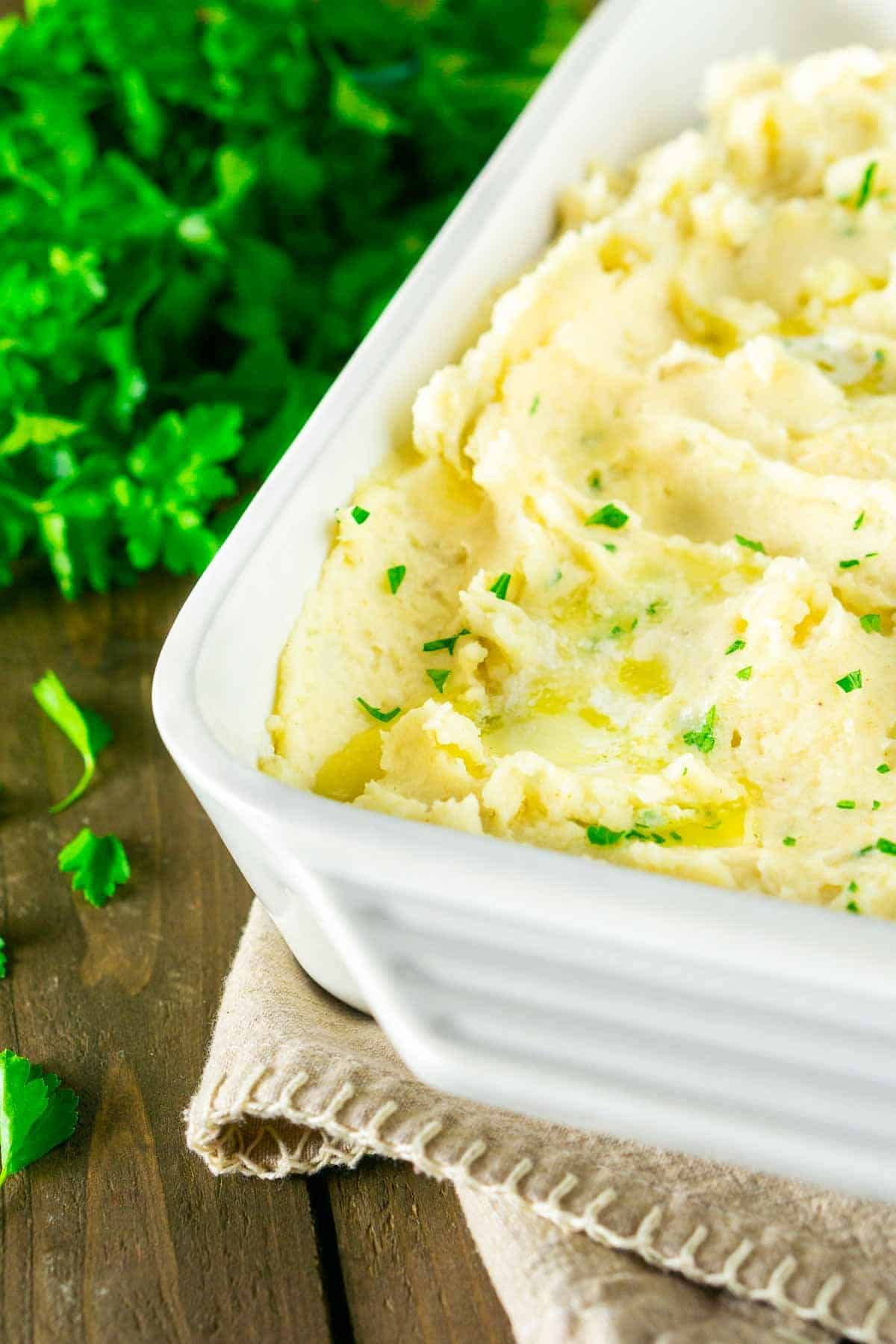 A pan of the best brown butter mashed potatoes with melted butter and chopped parsley.