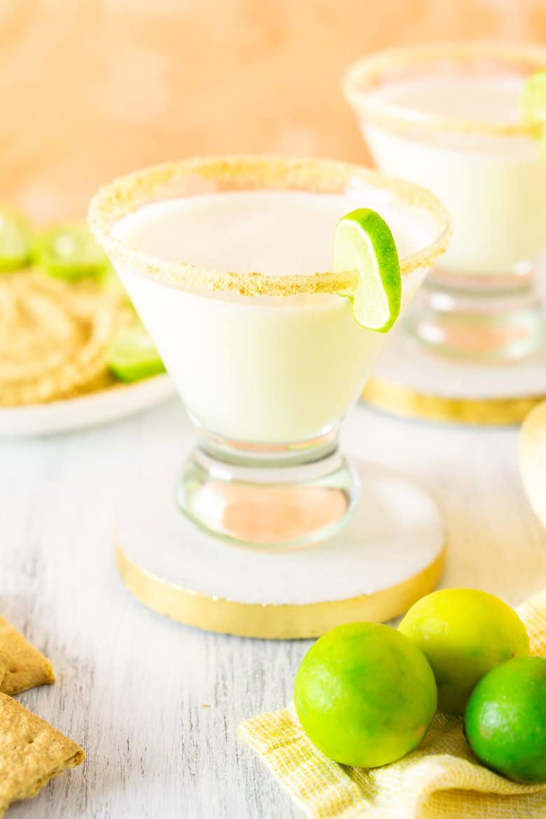 Two sparkling key lime pie martinis with graham crackers and key limes.