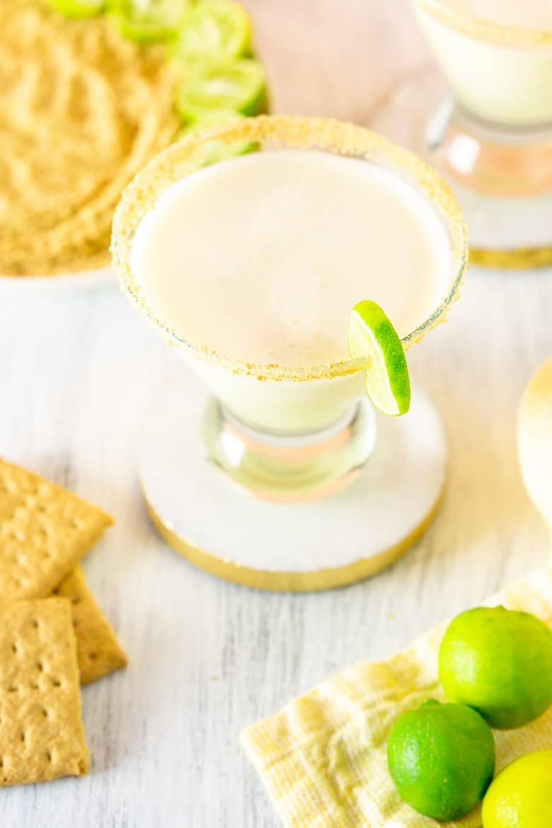 An aerial view of the sparkling key lime pie martini with a plate of crushed graham cracker crumbs and key limes.