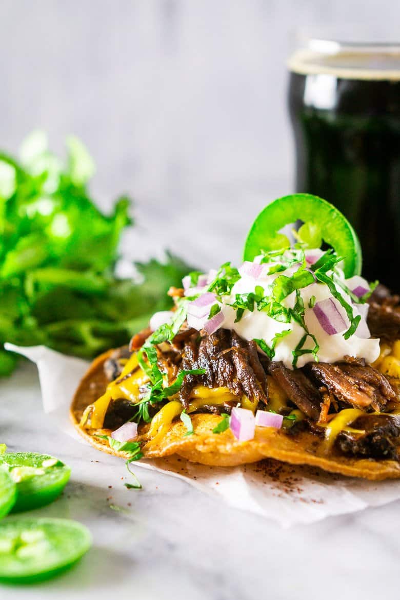 A tostada with beer-braised Mexican shredded beef with cilantro on the side.