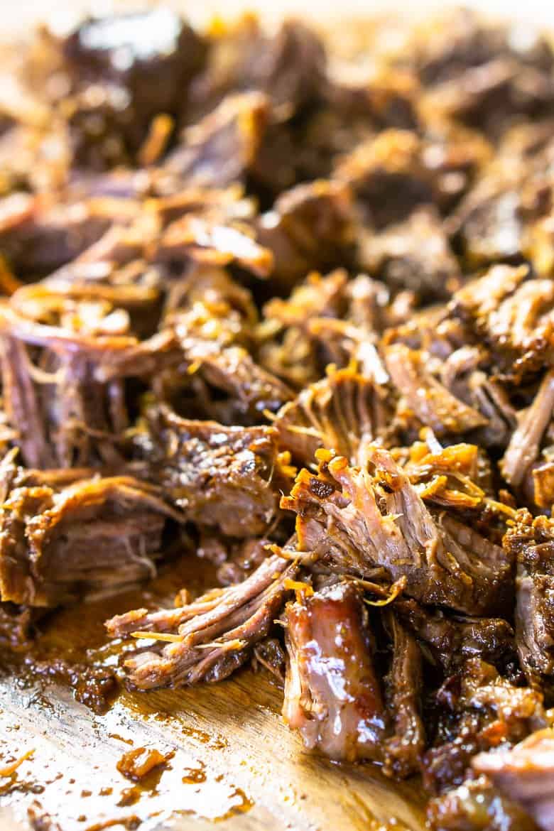 The beer-braised Mexican shredded beef on a wooden cutting board after being shredded.