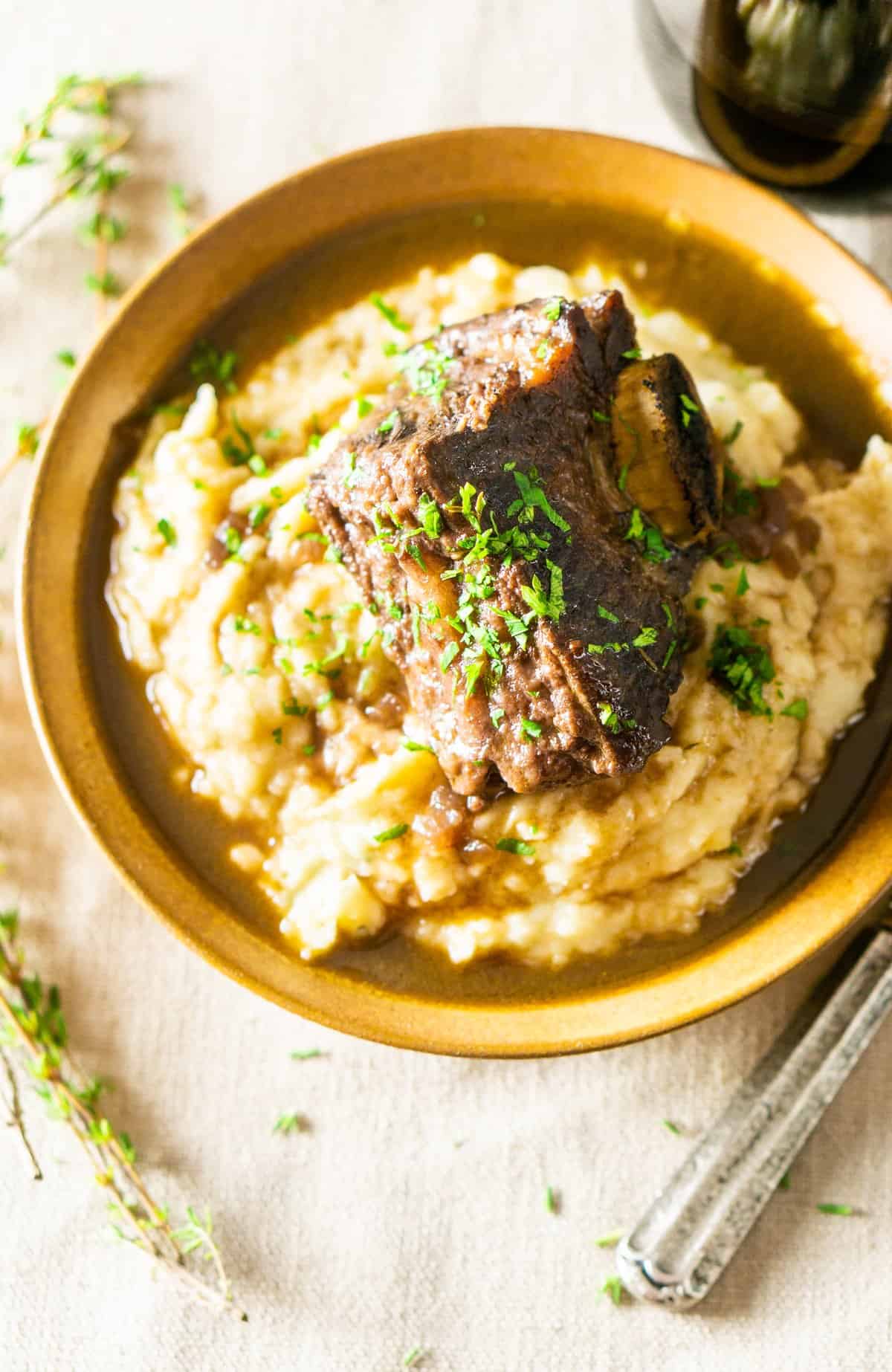 An aerial shot of the red wine-braised short ribs in a bowl of mashed potatoes.