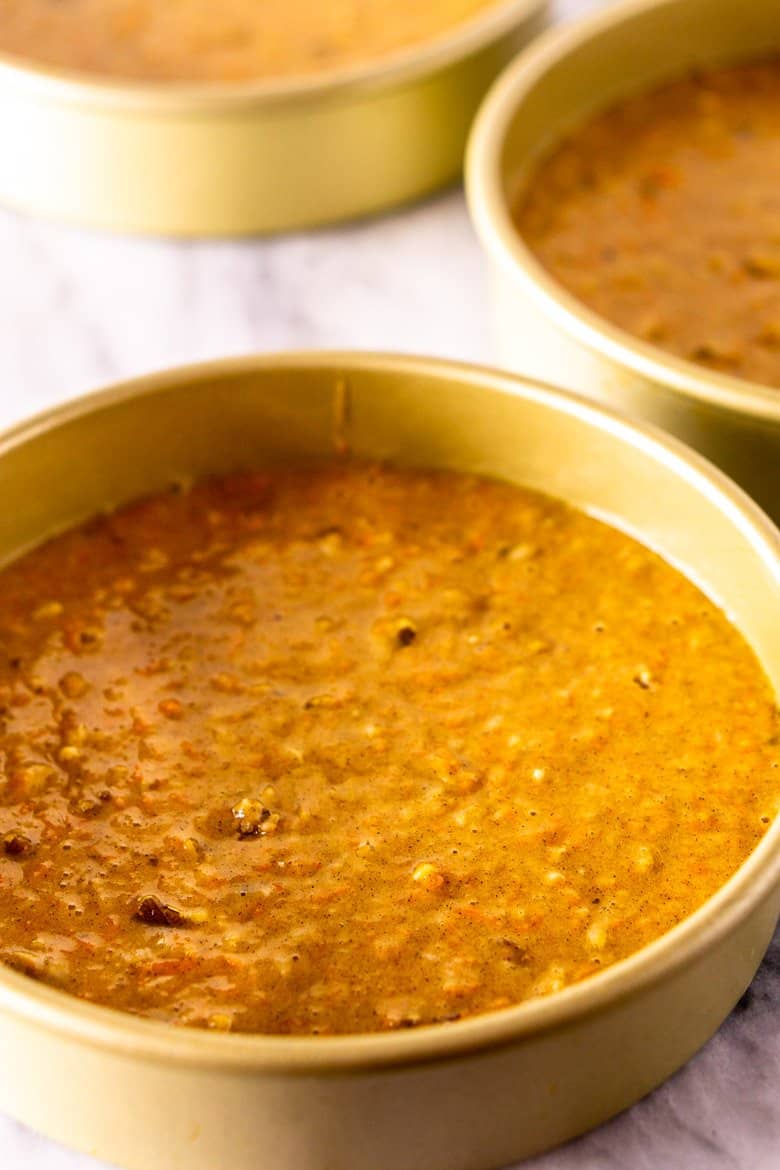 The poured carrot cake batter in three cake pans.