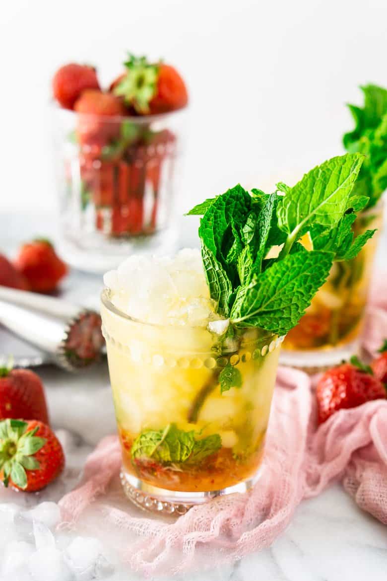 A glass of strawberry mint julep with another glass in the background.