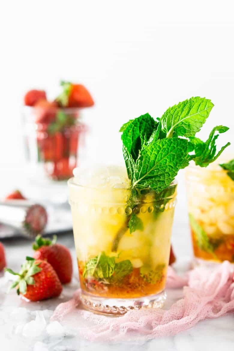 A strawberry mint julep with strawberries in the background.