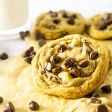 A brown butter chocolate chip cookie propped up with cookies surrounding it.