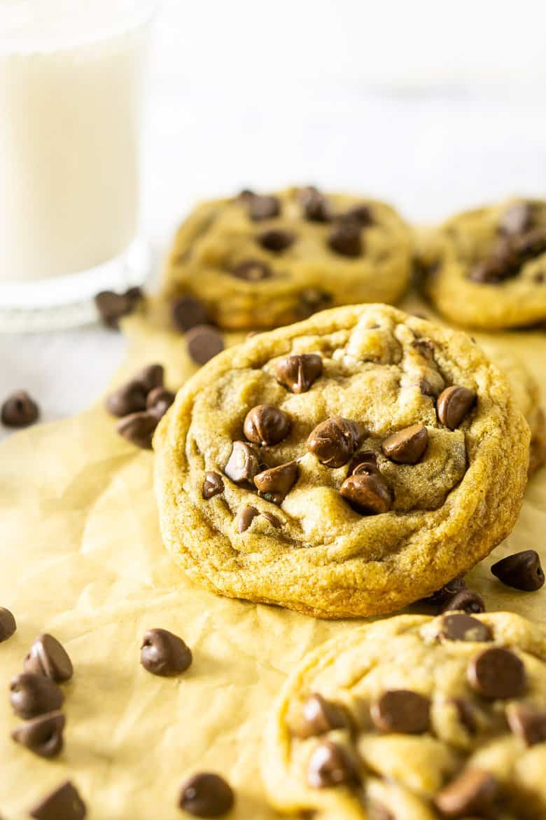 A brown butter chocolate chip cookie propped up with cookies surrounding it.