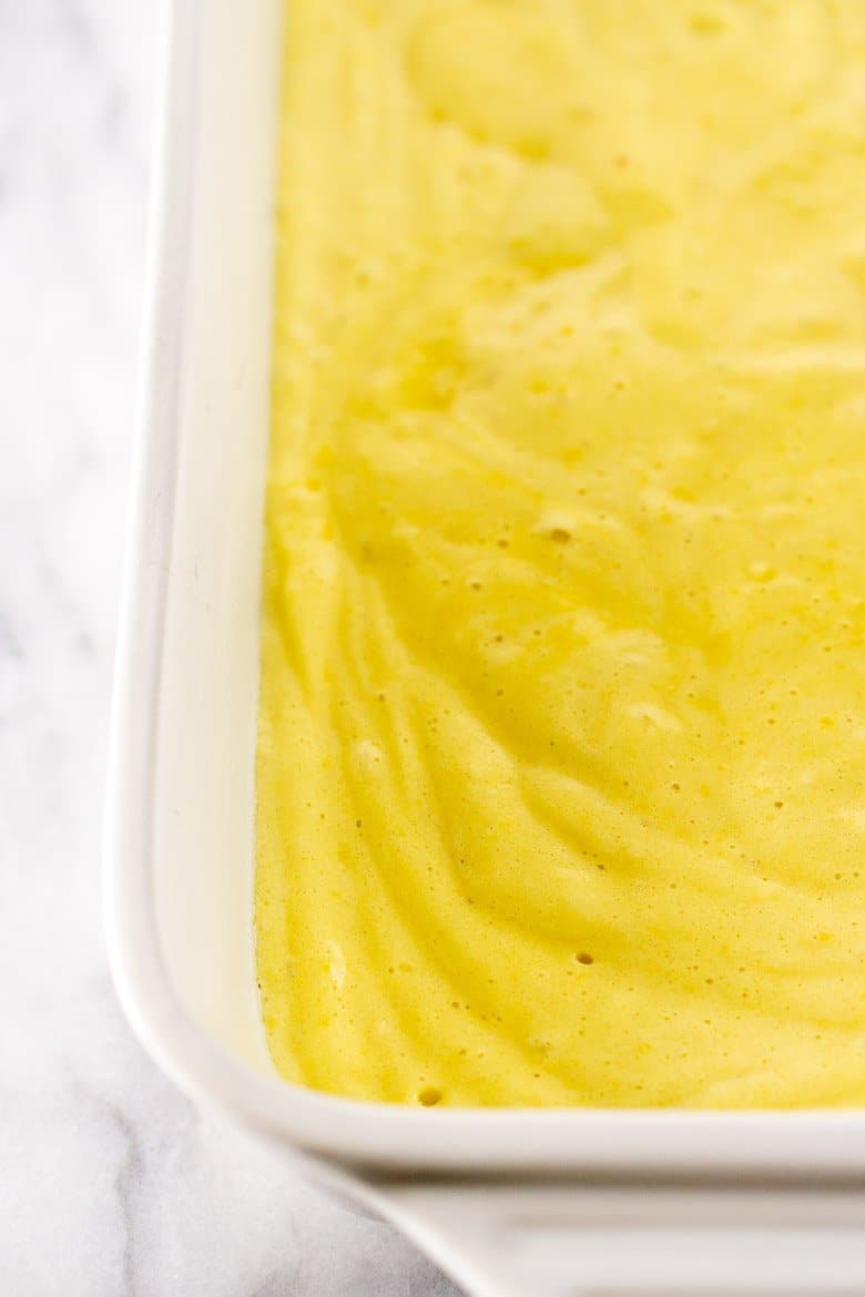 The spiced orange tres leches cake batter poured into a pan with air bubbles.
