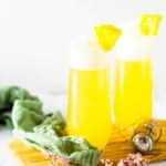 Two pineapple mimosas on a wooden board with flowers.