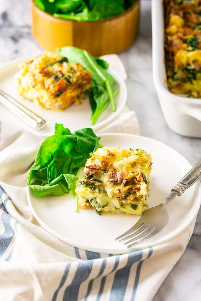 An aerial view of the bacon, Gruyere and spinach strata on a small plate with spinach.
