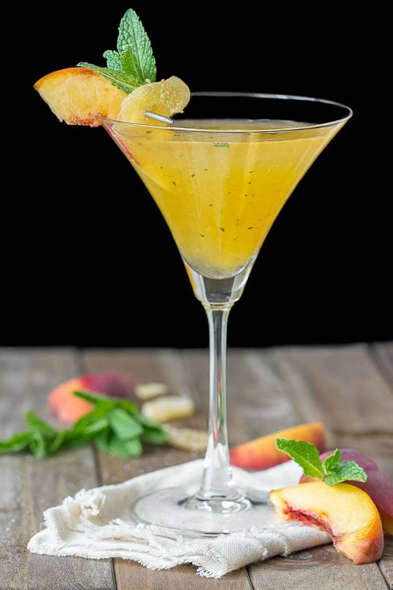 A ginger peach martini on burlap with peach slices.