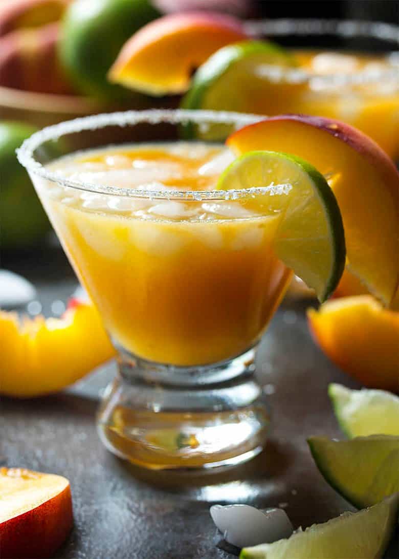 A fresh peach margarita with a lime and orange slice.