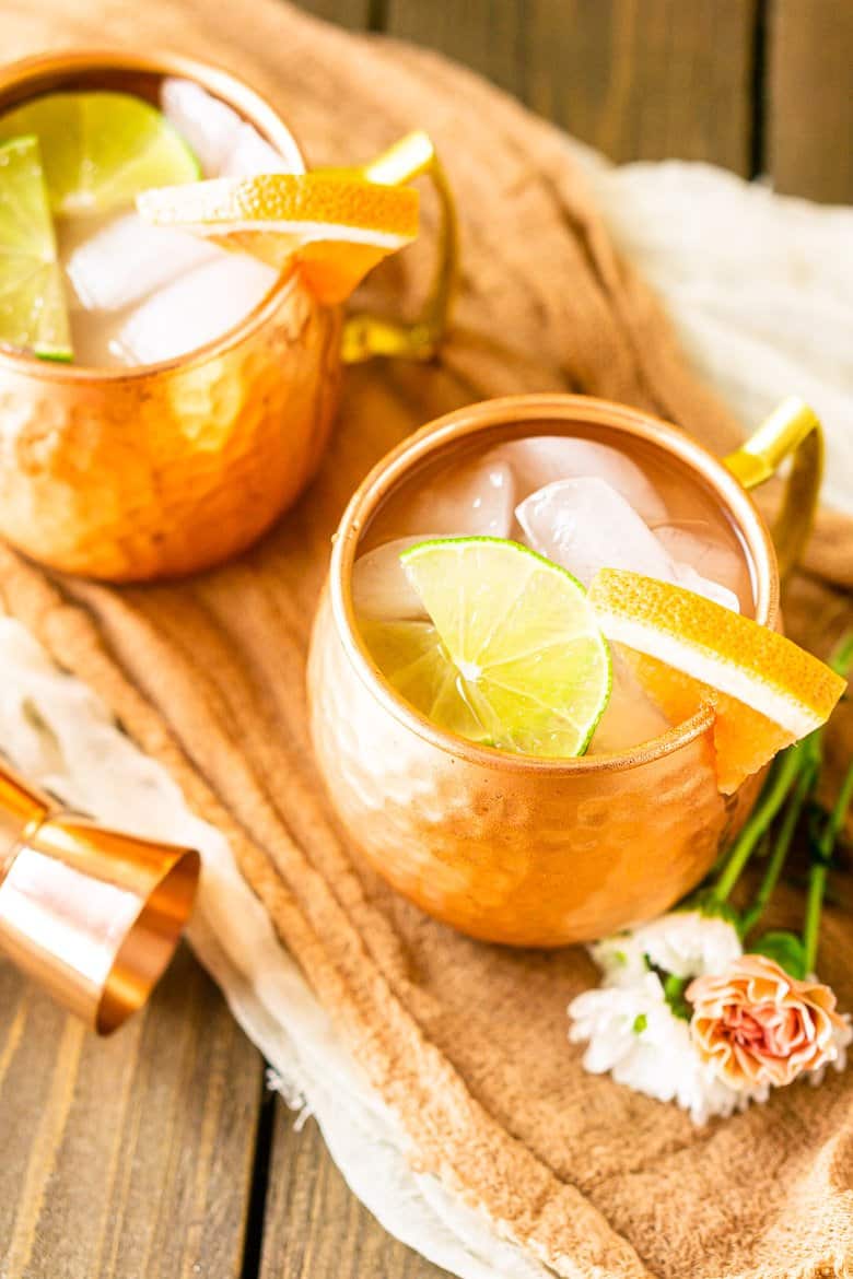 An aerial view of two grapefruit gin mules on cloth.