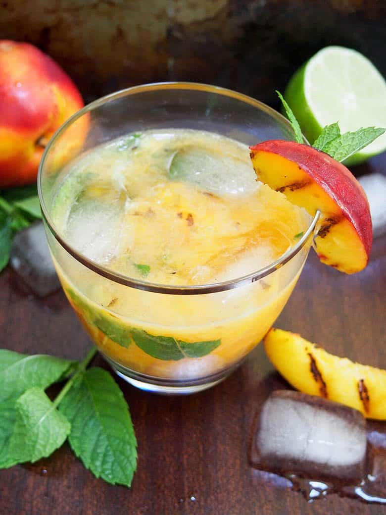 A grilled peach mojito with fresh peach slices.