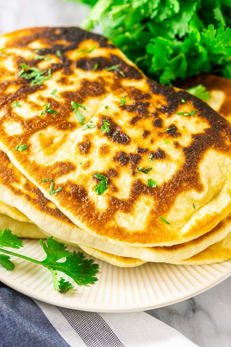 An aerial view of homemade garlic naan with a sprig of cilantro.