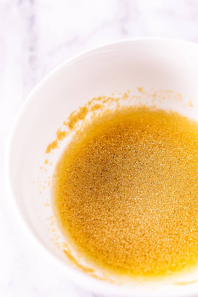 A bowl of water, honey and yeast to make the homemade garlic naan.