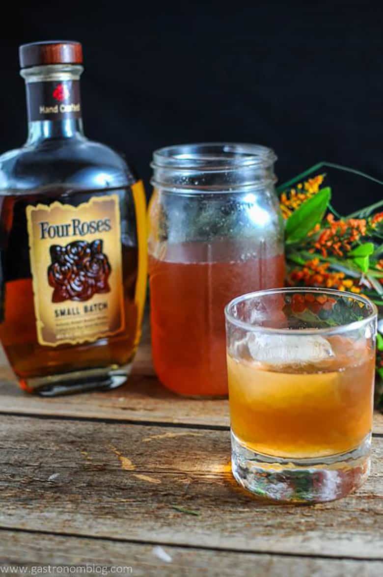 A peach and basil bourbon shrub on a wooden plank.