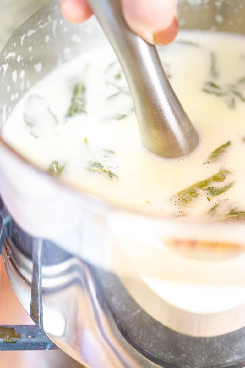 Using a muddler to muddle the mint leaves in the cream mixture.