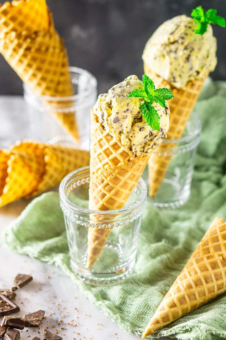 Several empty waffle cones surrounding waffle cones filled with fresh mint-chocolate chip ice cream.