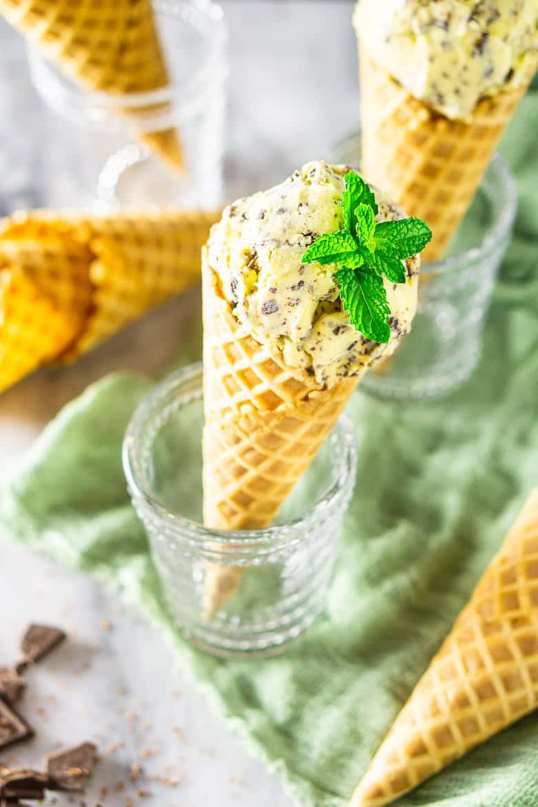 Looking down into a glass holding a waffle cone filled with fresh mint-chocolate chip ice cream.