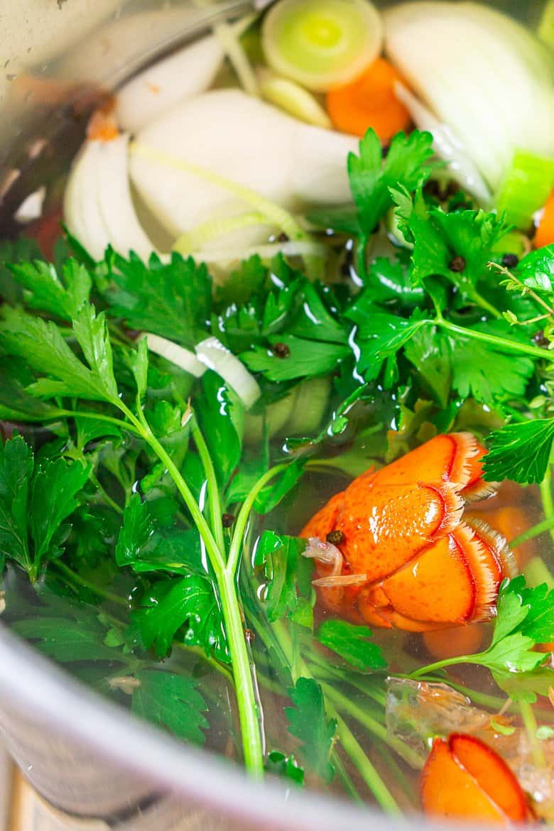 The sea fish shells and aromatics in a large pot to cook for the homemade seafood stock.