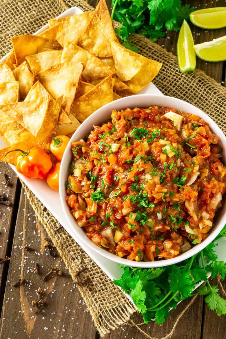 An aerial view of a bowl of Jamaican jerk salsa on a white plate with burlap.