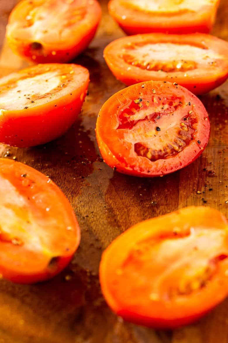 Sliced tomatoes on a cutting board ready to roast.