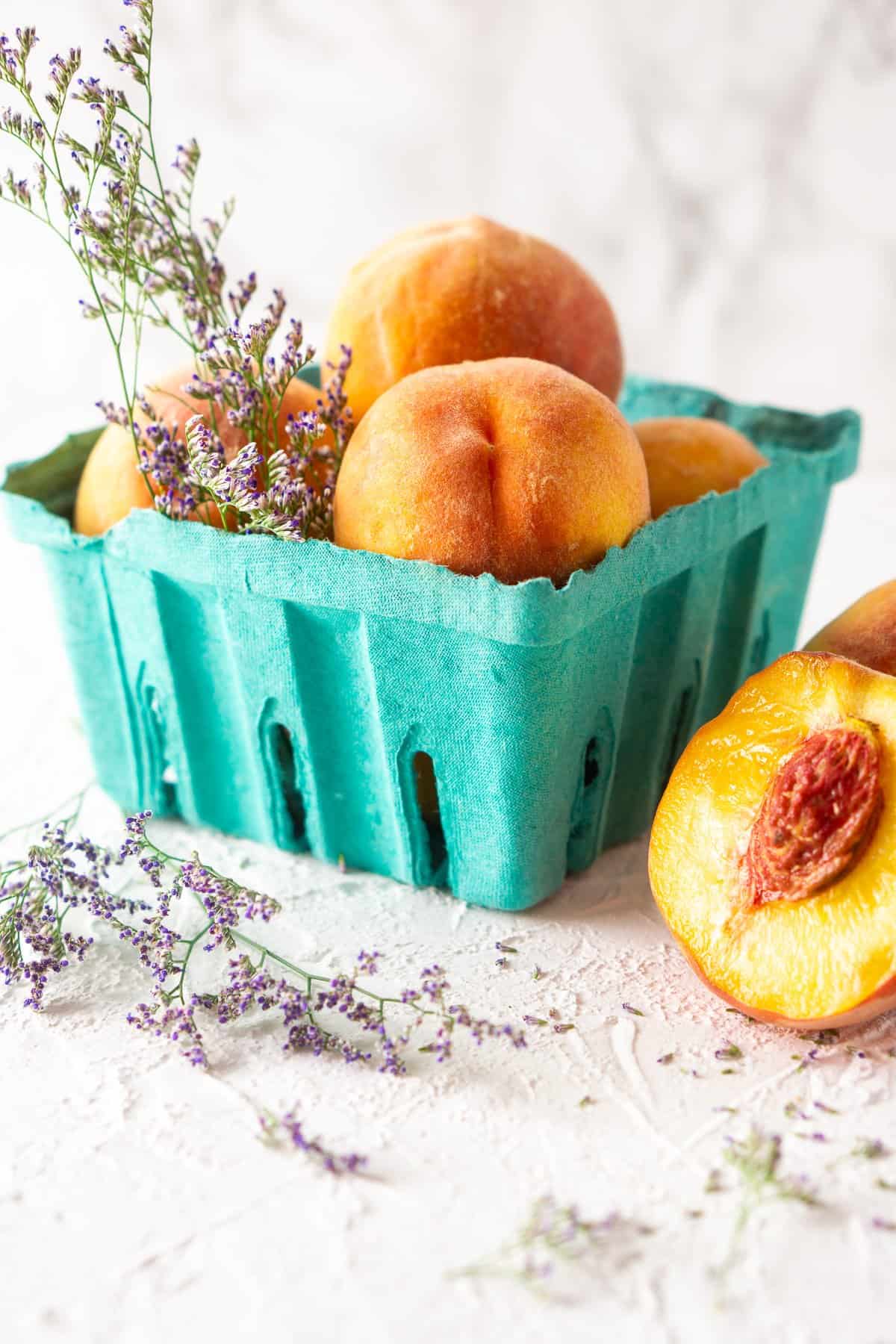 Palisade peaches in a teal container on a white board.