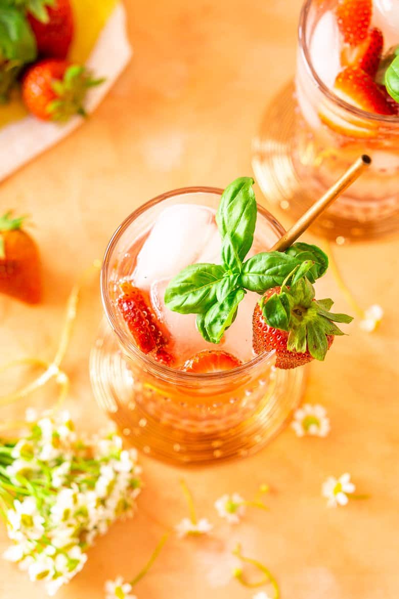 Aerial view of a strawberry-basil Tom Collins with flowers around it.
