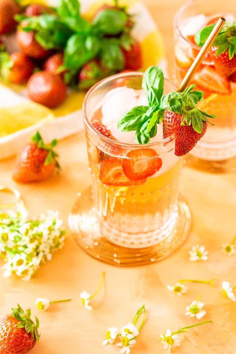 Looking down into a strawberry-basil Tom Collins with fresh strawberries and basil.