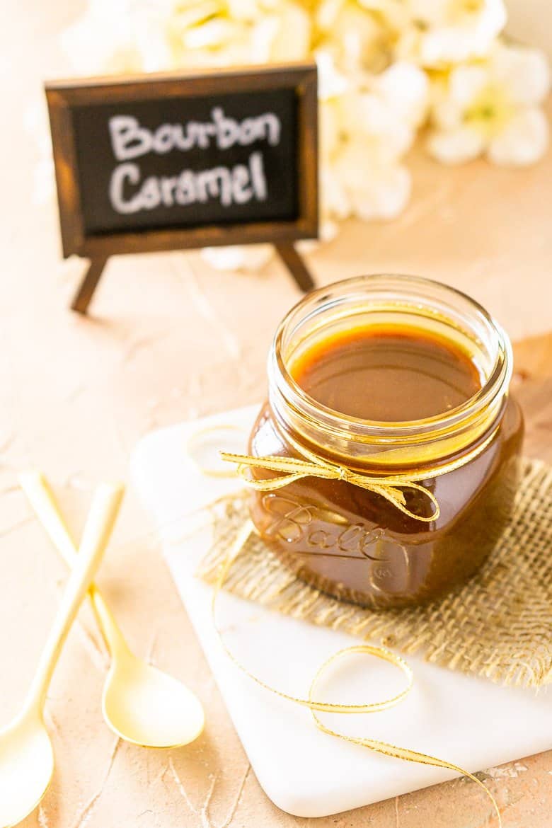 A jar of bourbon caramel sauce from up top on burlap and a marble tray.